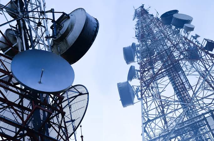 Satellite dishes and a cellular tower at dusk